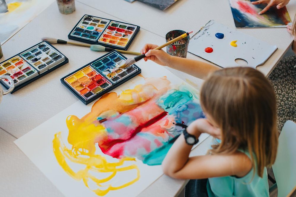 Ett barn målar med vattenfärger