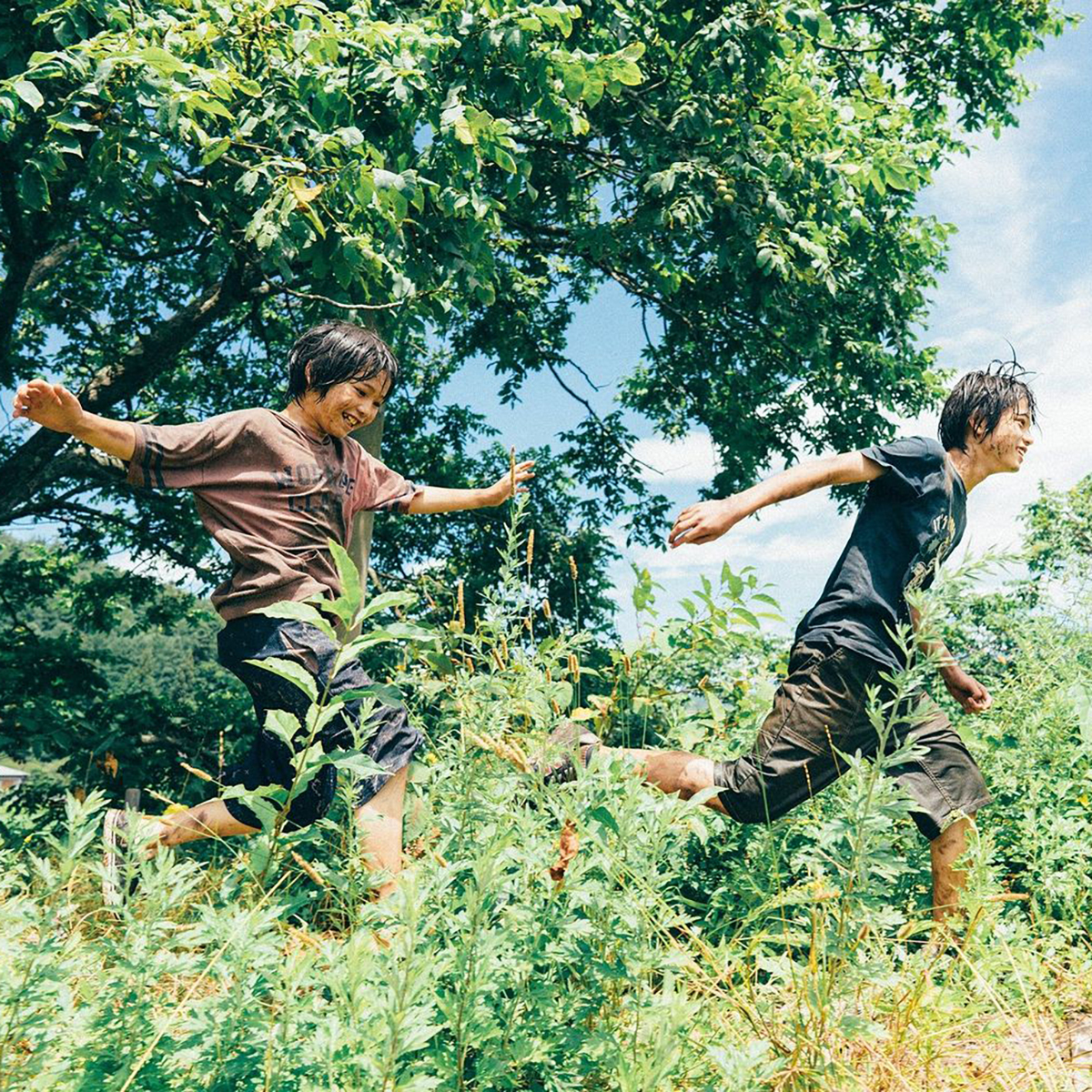 Två unga personer springer genom grönska.