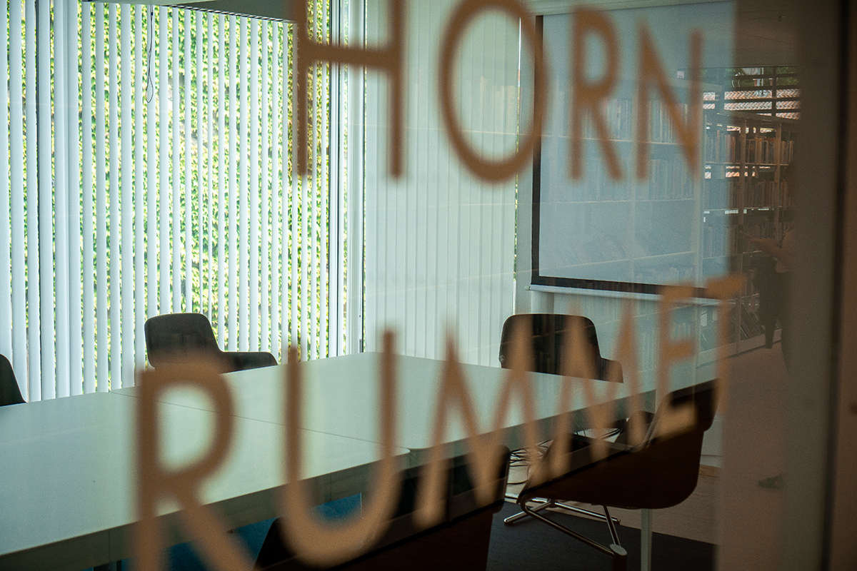 Bild tagen in genom ett fönster till konferensrum där texten hörnrummet syns suddigt i förgrunden.