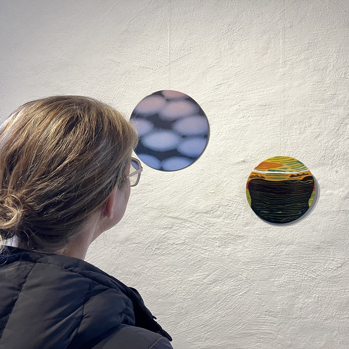 En person tittar på två runda konstverk.