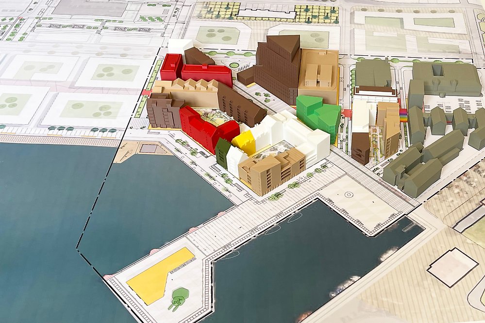 Bild tagen snett uppifrån på ett antal modellbyggnader i olika färger. Byggnaderna står på en utskriven karta och bildar tillsammans en del av en stadsdel.