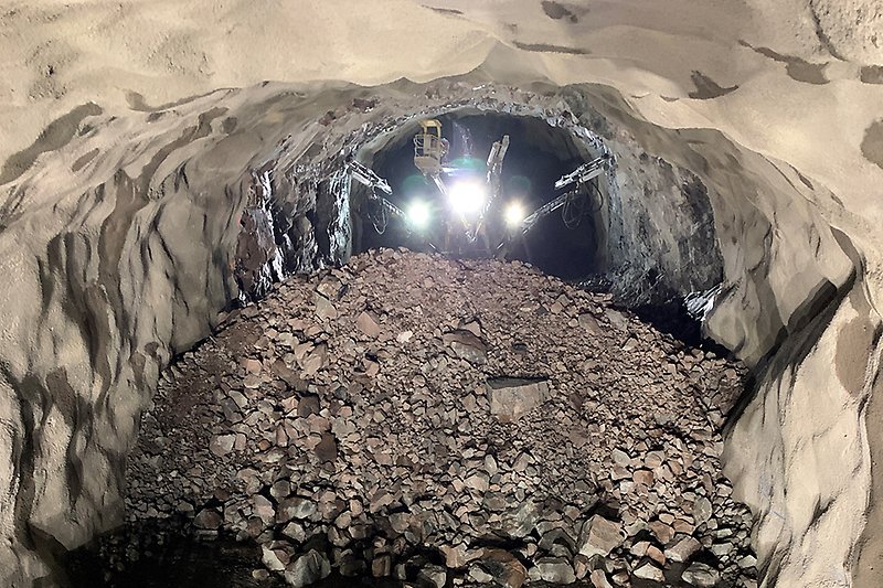 Foto inifrån Varbergstunnelns spårtunnel när hela tunneln är färdigsprängd. Bergmassor i förgrunden. 